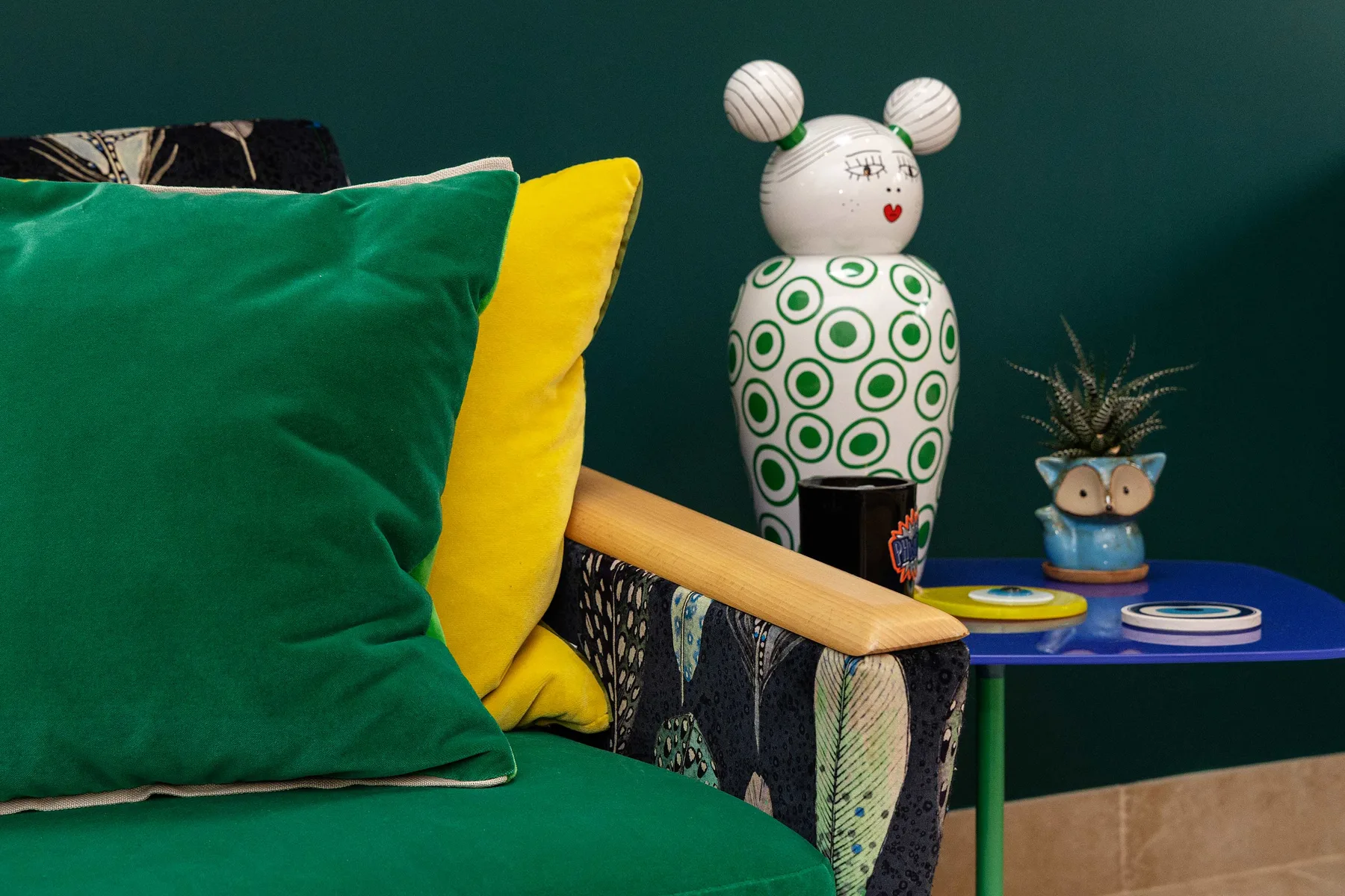 Una zona de asientos colorida con cojines vivos junto a una mesa azul pequeña.