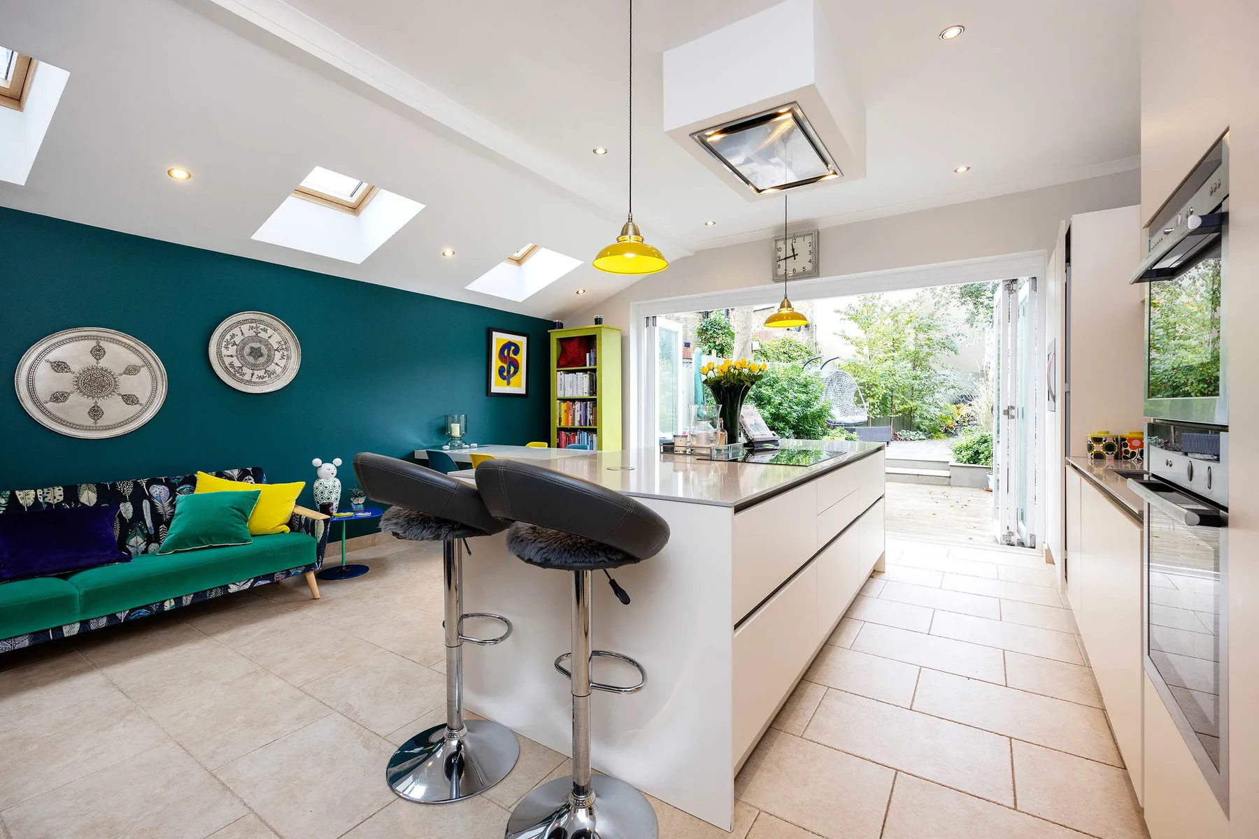 Una luminosa cocina abierta al salón, con una isla central y asientos coloridos.