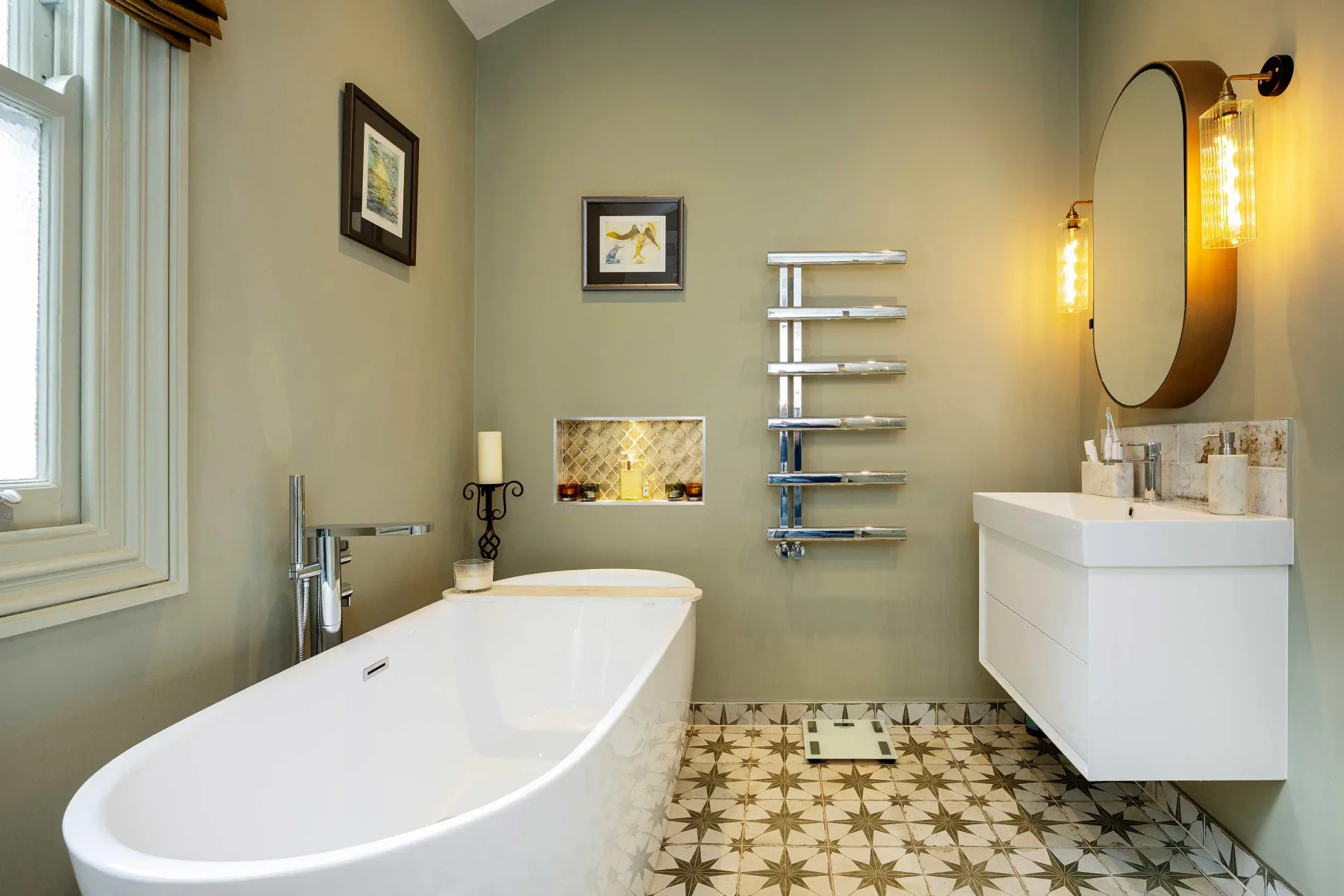 Un baño con bañera, lavabo y suelo de baldosas estampadas.