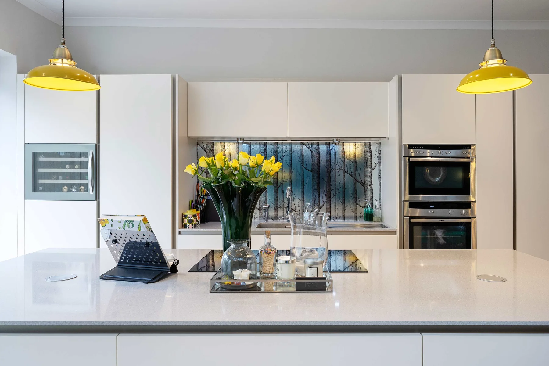 Una cocina moderna y luminosa con una amplia isla y lámparas colgantes amarillas.