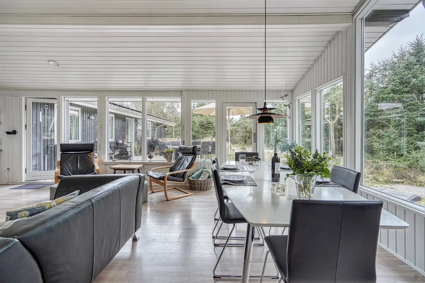 A bright dining area with a long table beside large windows.