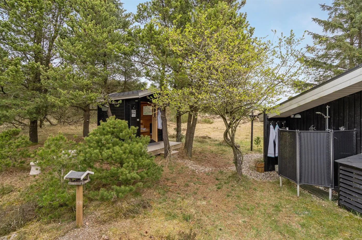 Outdoor yard with trees, a small outbuilding, and a fenced shower area.