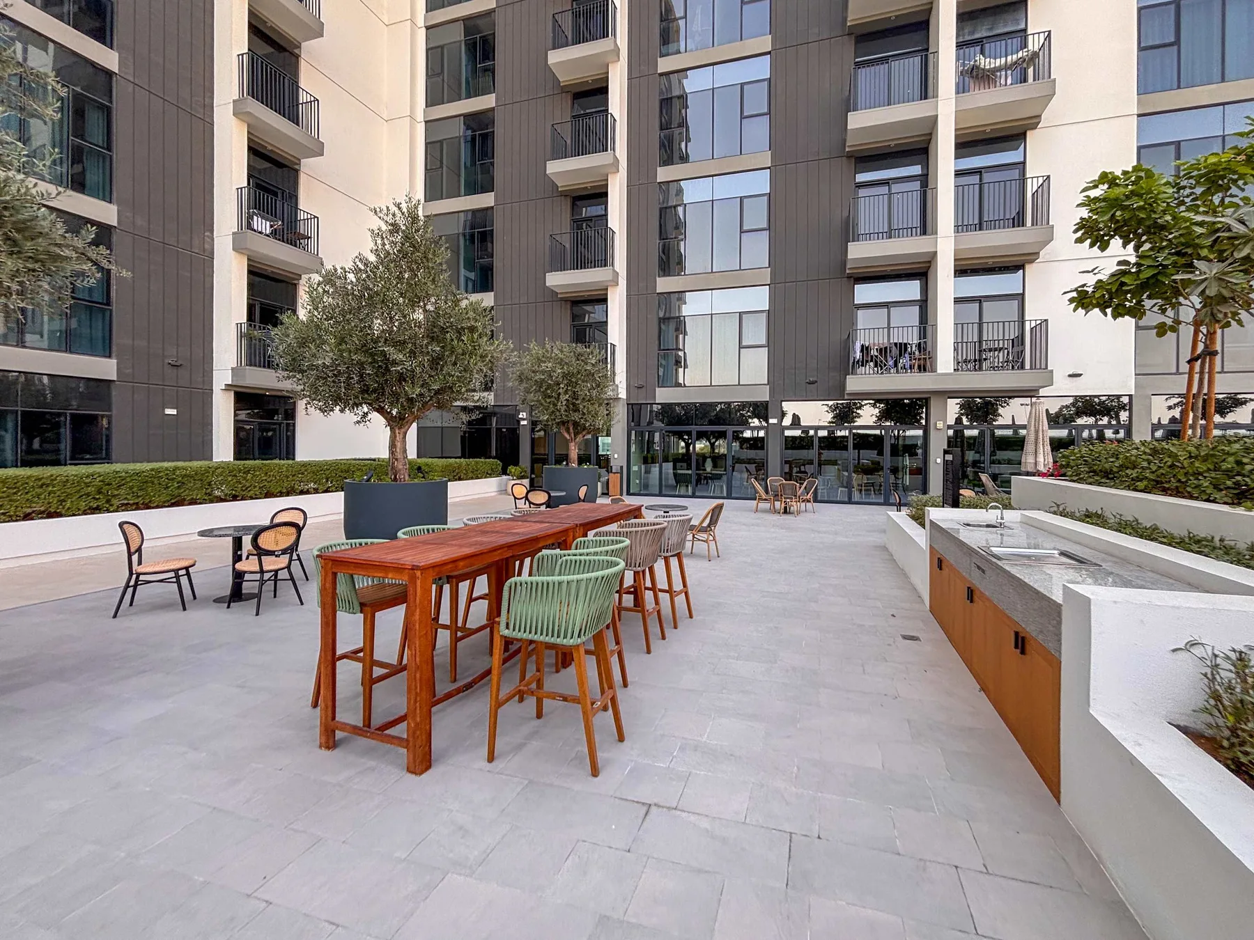 Un patio pavimentado con mesas y asientos al aire libre junto a un edificio moderno.