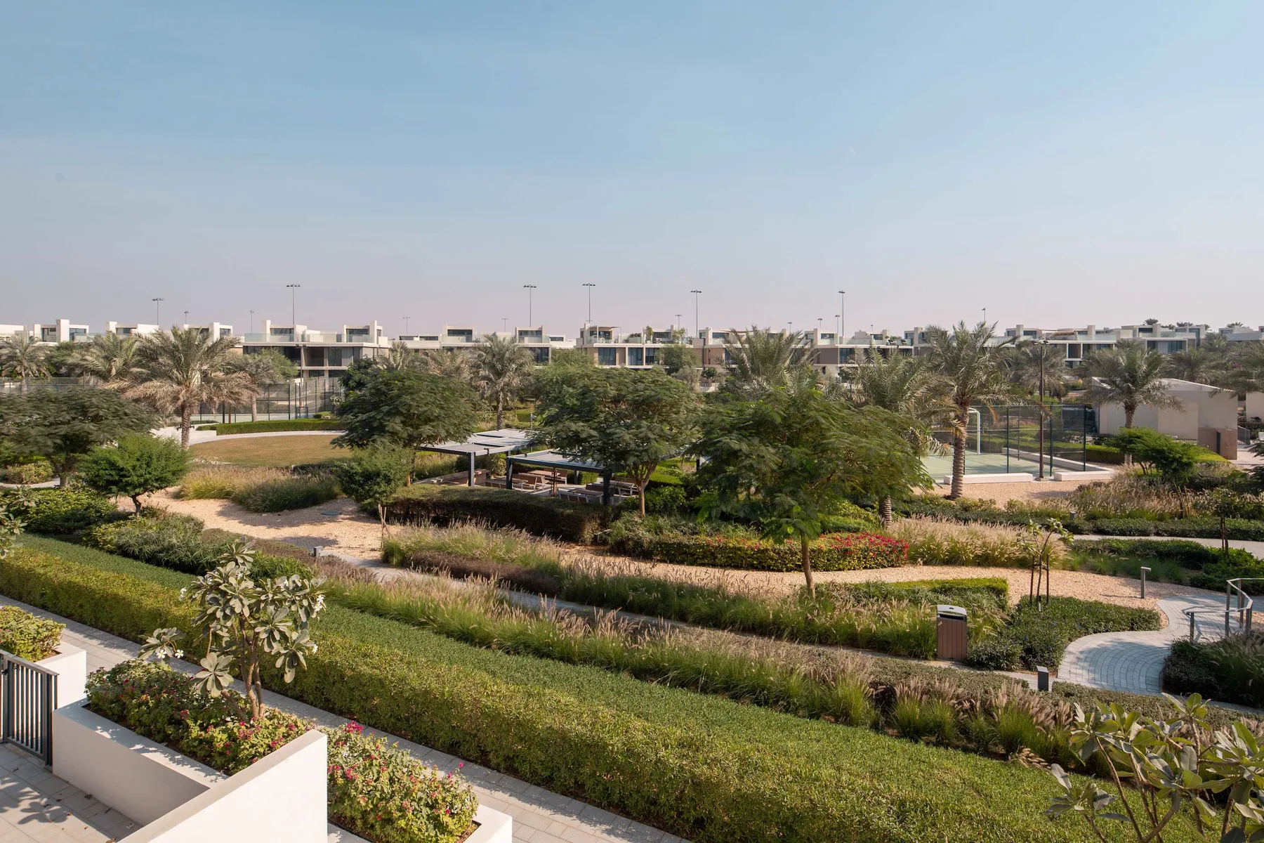 Un jardín exterior ajardinado con senderos sinuosos, arbustos y árboles.
