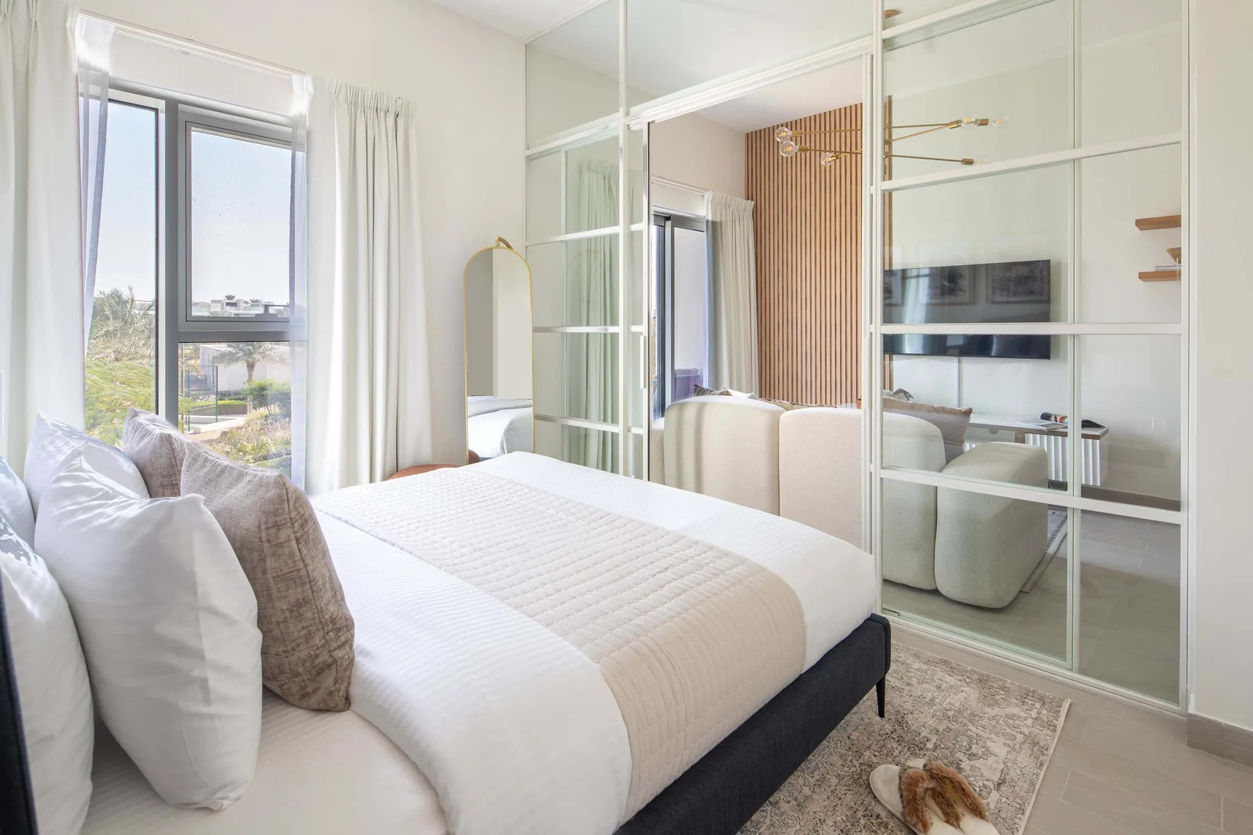 Un dormitorio luminoso con una cama bien tendida y puertas de armario con espejo.