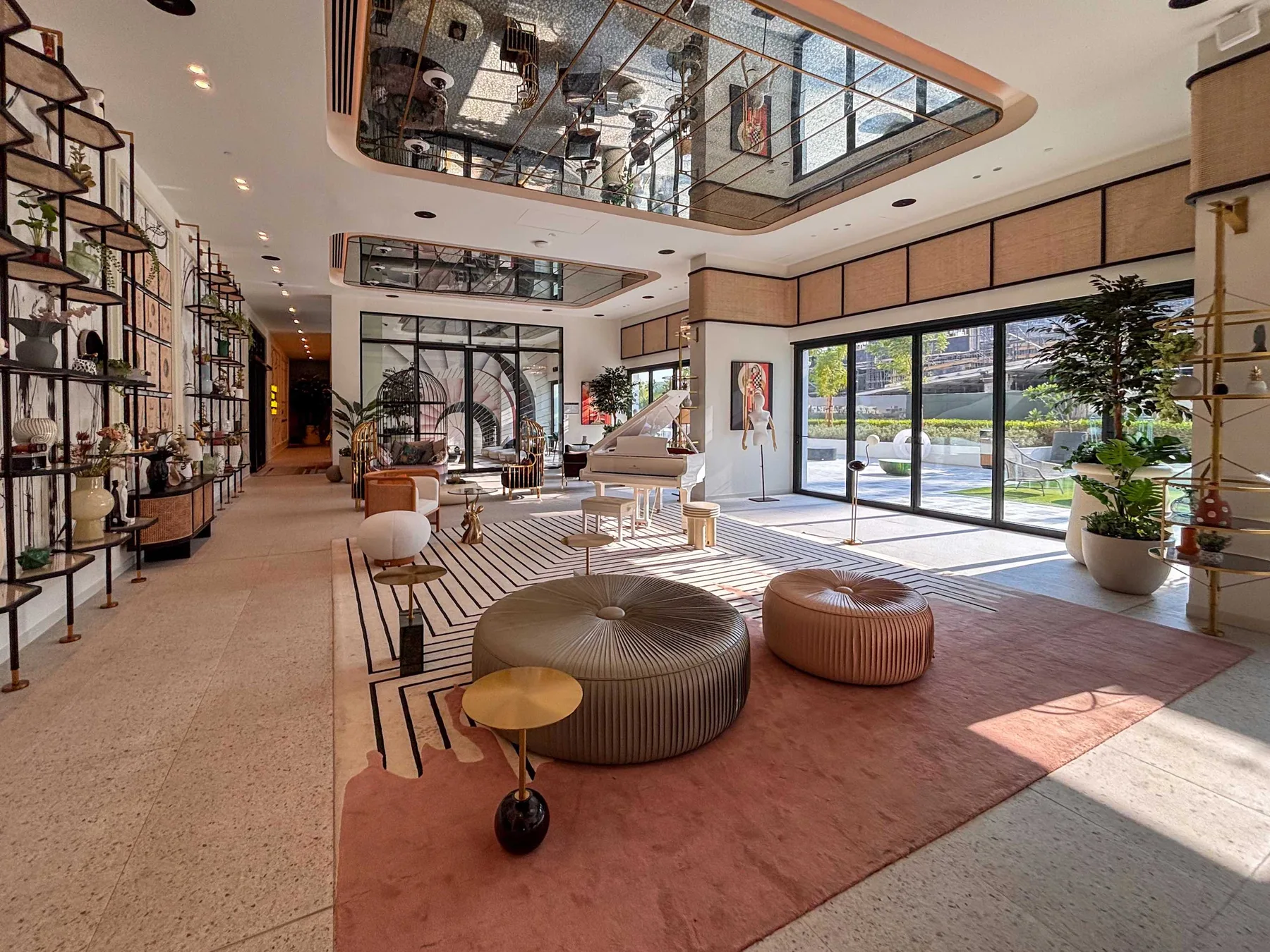 Un salón moderno y luminoso con asientos bajos, estanterías decorativas y grandes puertas de vidrio.