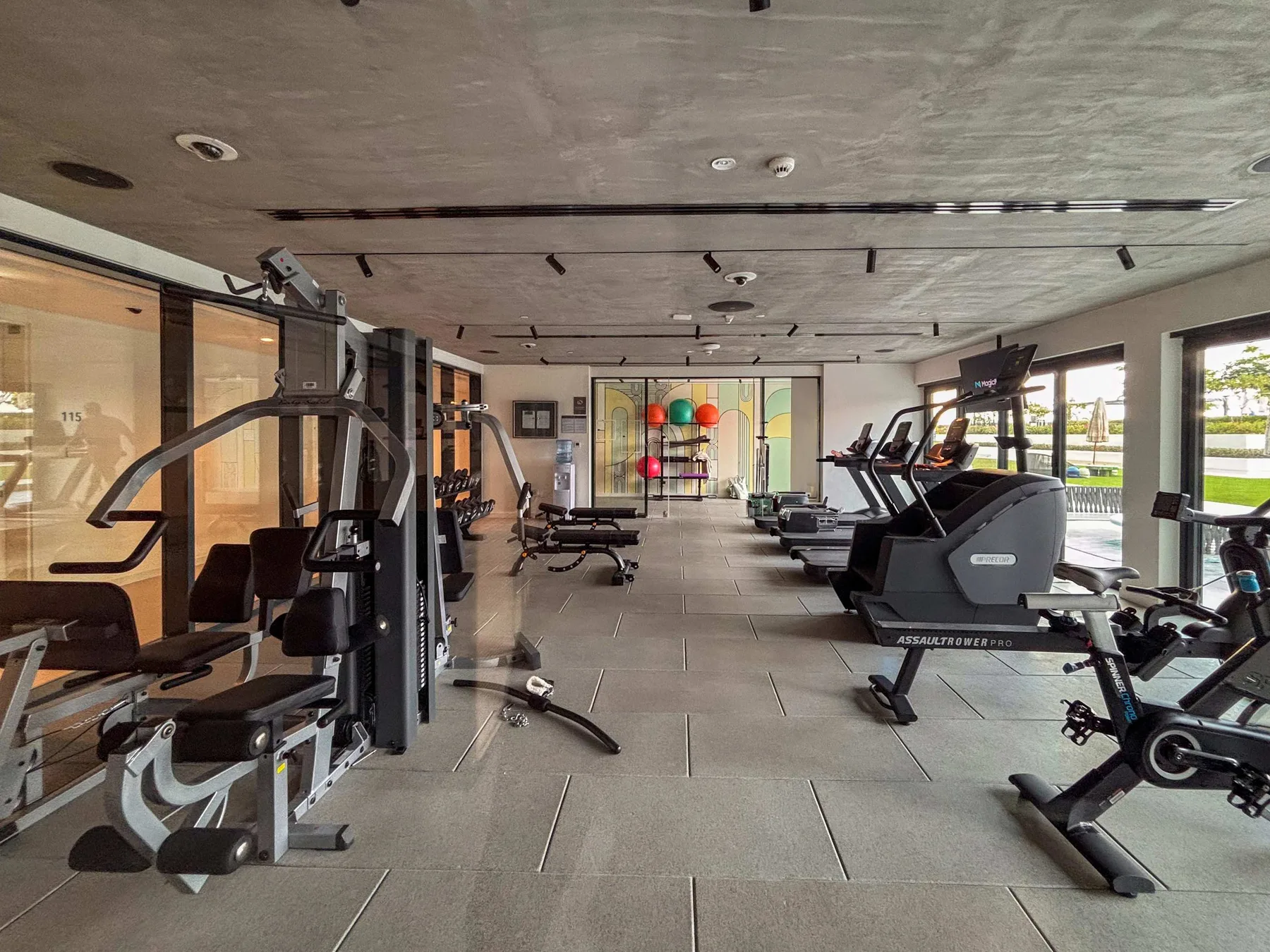 Un gimnasio con máquinas de ejercicio y pesas distribuidas por la sala.