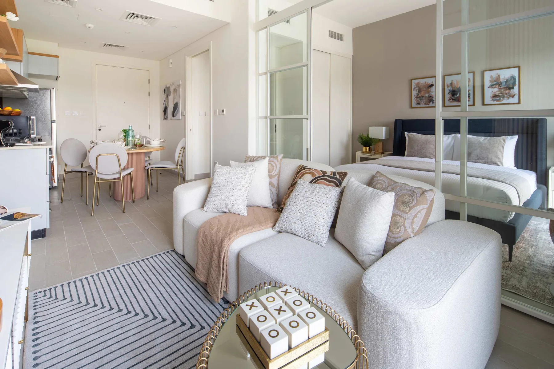 Una luminosa sala de estar de planta abierta con un sofá y una mesa de comedor junto al dormitorio.