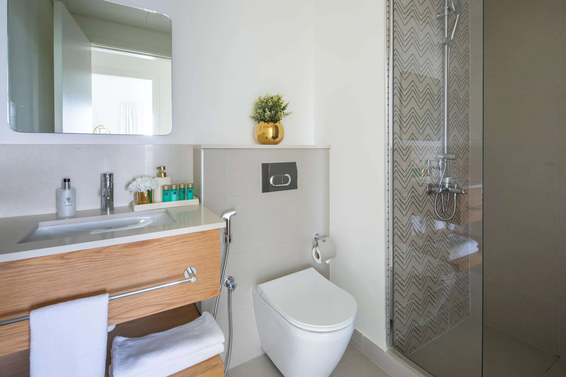 Un baño moderno con un tocador de frente de madera y una ducha acristalada.