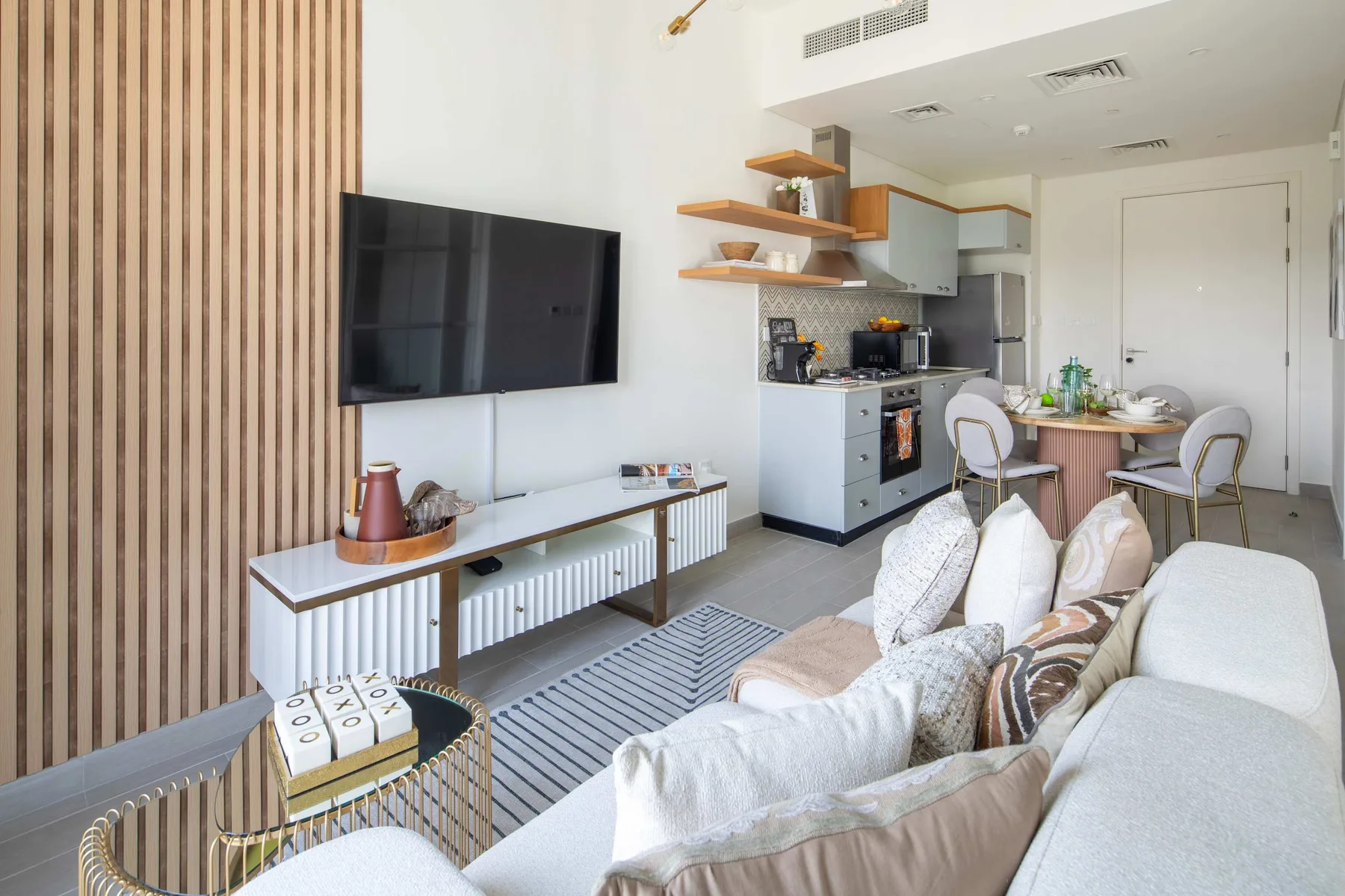 Sala de estar con televisión, asientos y una cocina abierta.