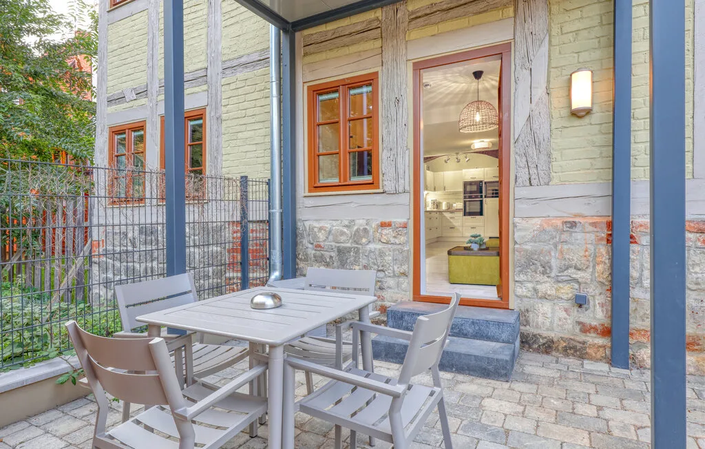 An outdoor patio with a dining table and seating beside a glass door.
