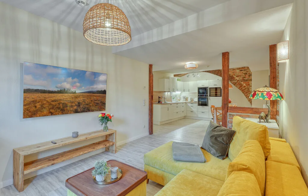 A bright living room with yellow seating and an open kitchen in the background.