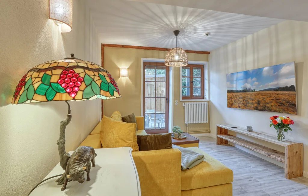 Una sala luminosa con asientos amarillos, lámparas decorativas y un cuadro de paisaje en la pared.