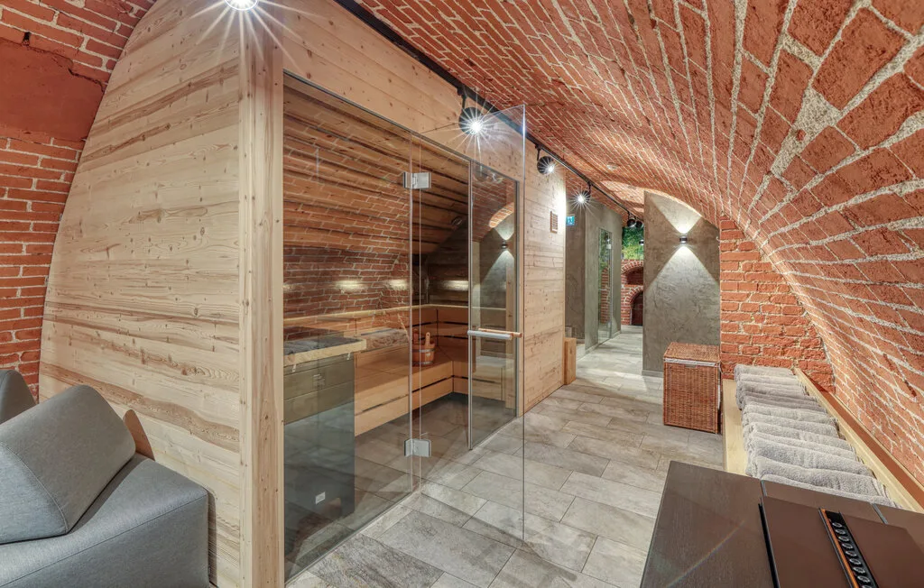 A tiled hallway runs past a glass shower enclosure beneath a curved brick ceiling.