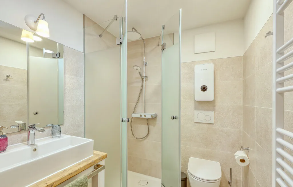 A tiled bathroom with a glass shower, sink, and toilet.
