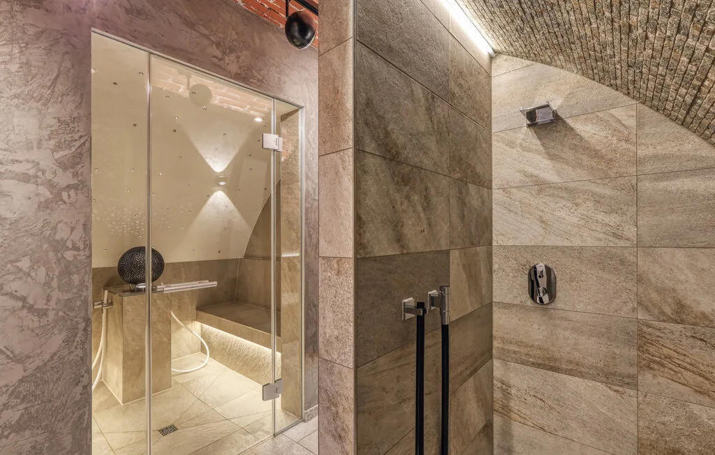 A tiled bathroom with glass shower enclosures and a wall-mounted showerhead.