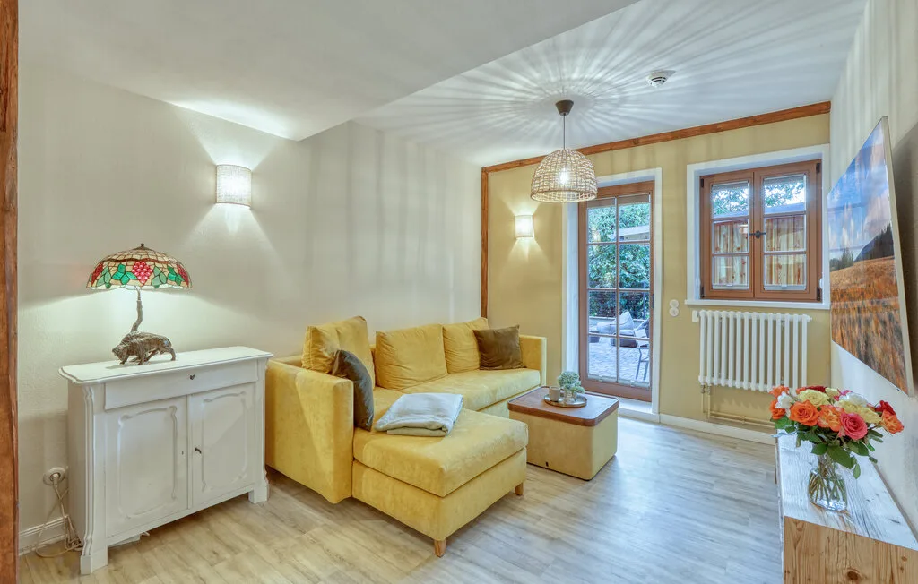 A bright living room features yellow seating beside a glass door and windows.