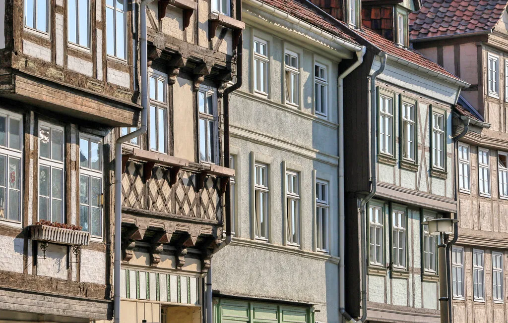 A row of historic-looking townhouses with tall windows and a wooden balcony.
