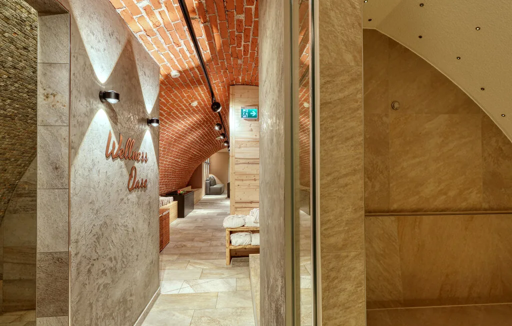 A stone-lined corridor has a curved brick ceiling and a bench.