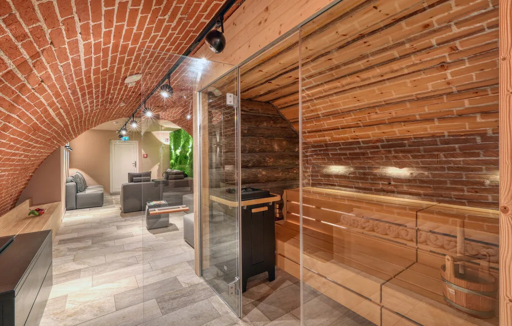 A basement spa area with a glass-fronted sauna and seating beyond.
