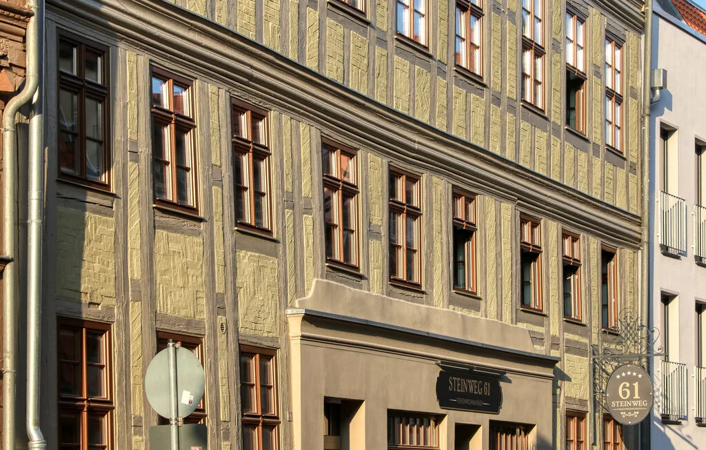 A sunlit historic building facade with rows of tall windows.