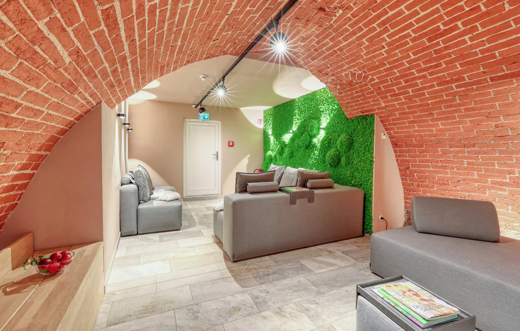 A lounge with seating beneath a curved brick ceiling and beside a green wall.