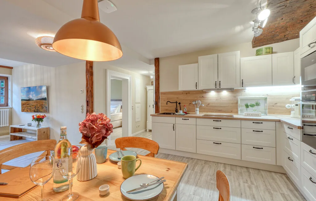 A bright kitchen and dining area with white cabinets and a wooden table.