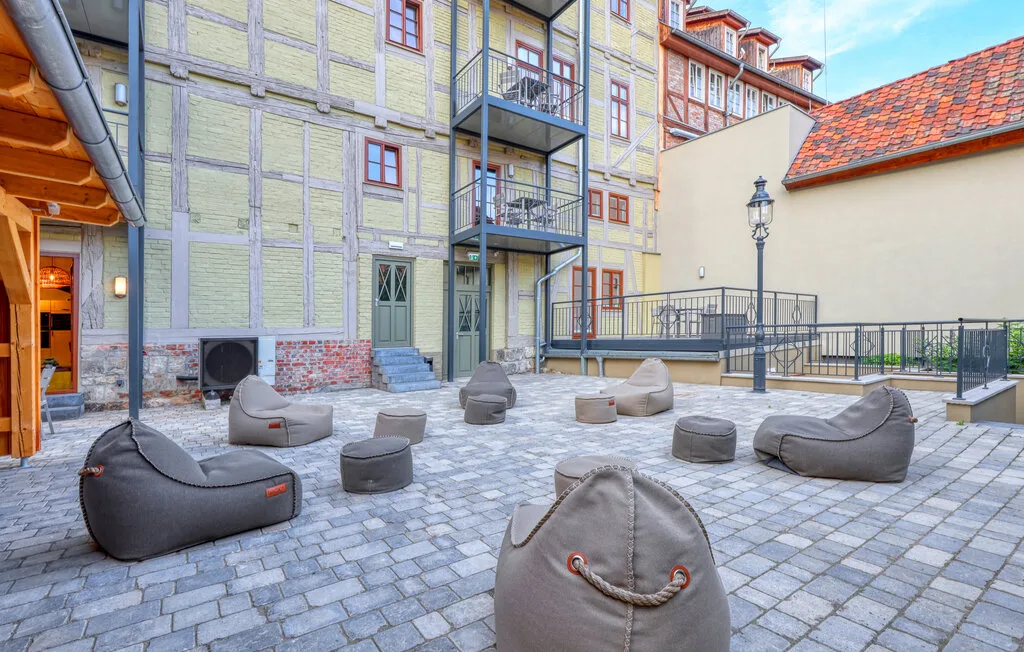 A paved courtyard with scattered outdoor seating and balconies overlooking the space.