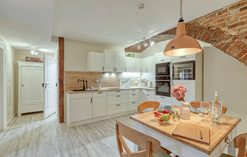 Una cocina luminosa con gabinetes blancos y una mesa de madera.