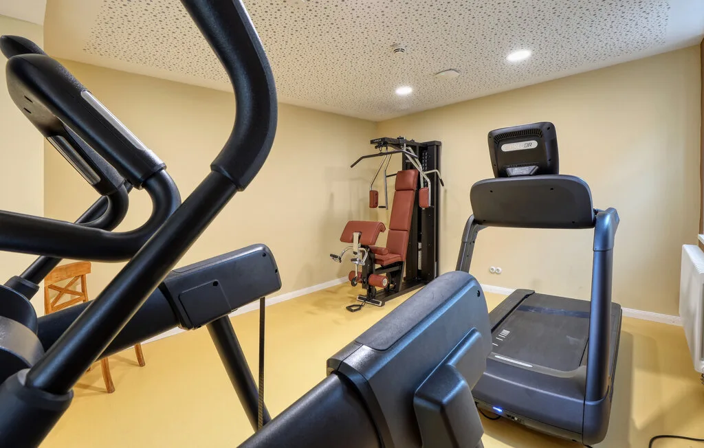 A compact exercise room with cardio machines and weight-training equipment.