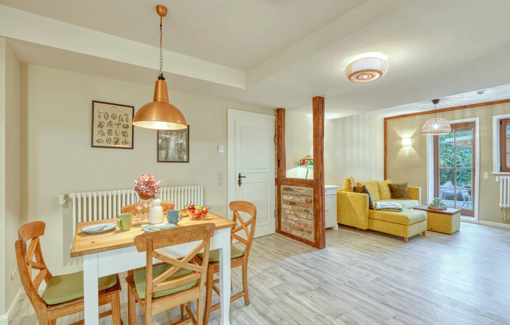 A dining area opens onto a living room with yellow seating and large windows.