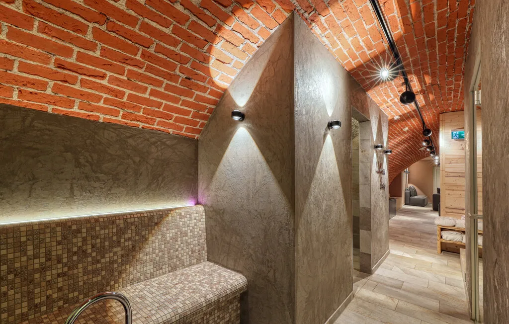 A brick-vaulted corridor with wall lights and a tiled bench.
