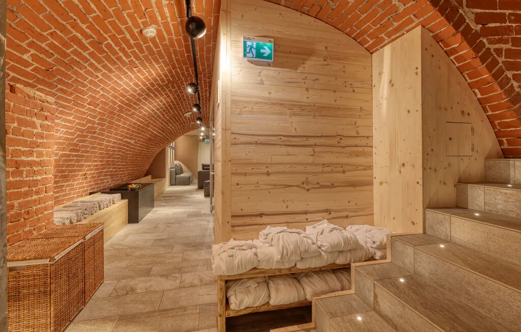A brick-vaulted interior hallway with a wooden sleeping nook and stone steps.