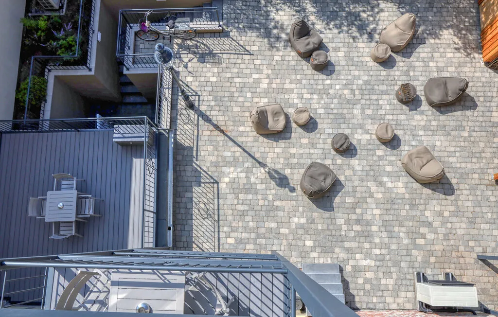 A paved outdoor terrace has scattered cushioned seating and metal railings.