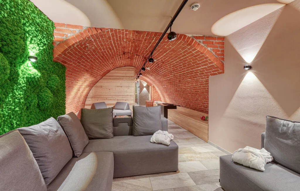 A lounge with seating beneath a curved brick ceiling and a green wall.