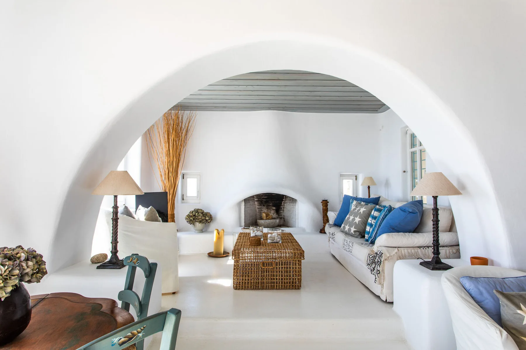 A bright living room with seating arranged around a central fireplace.