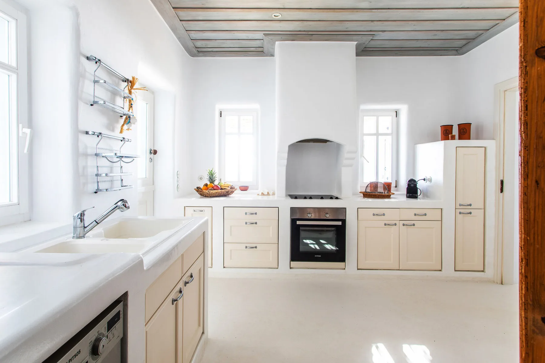 A bright kitchen with pale cabinets, a countertop oven, and a central cooking alcove.