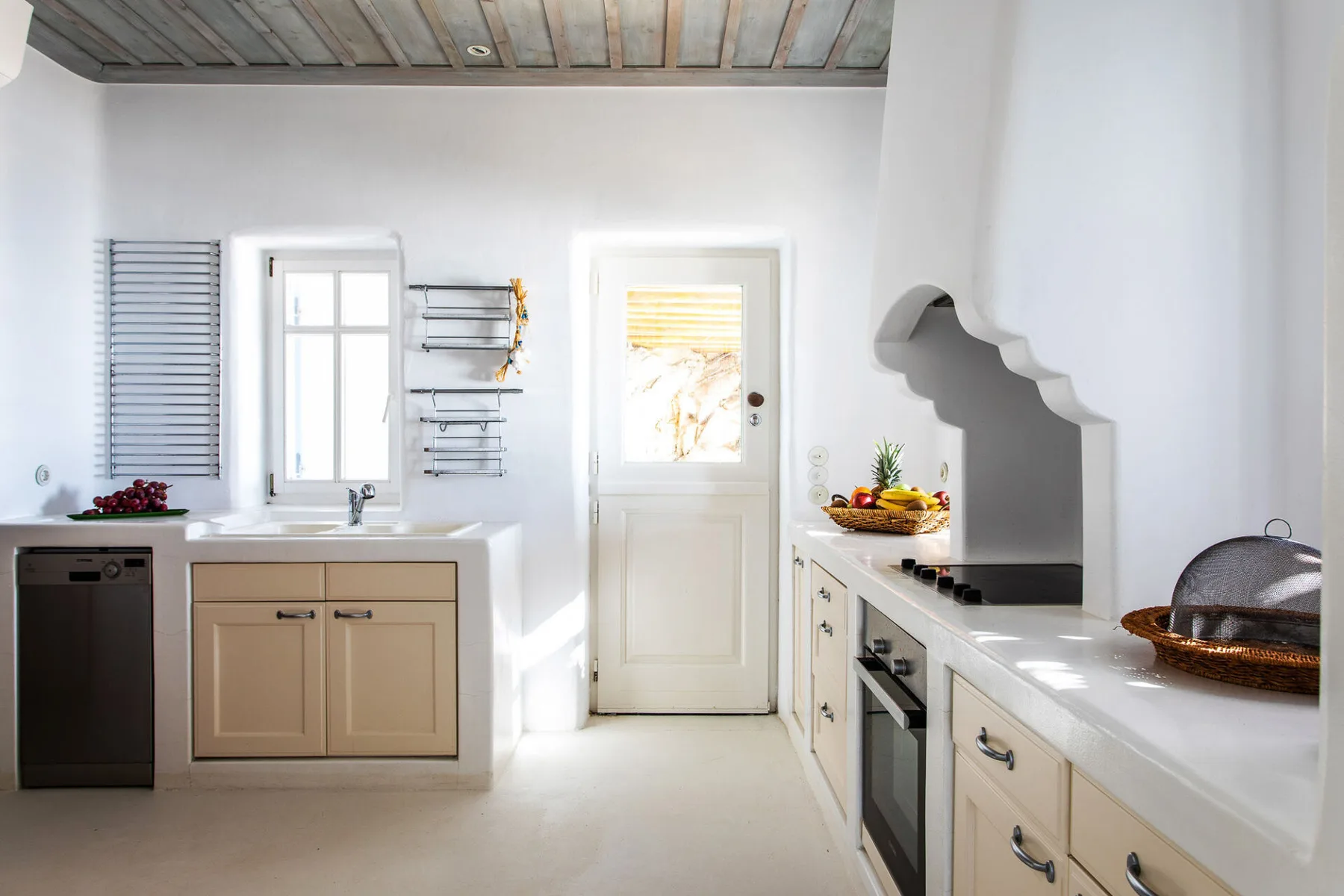A bright kitchen with pale cabinets, a countertop, and a door.