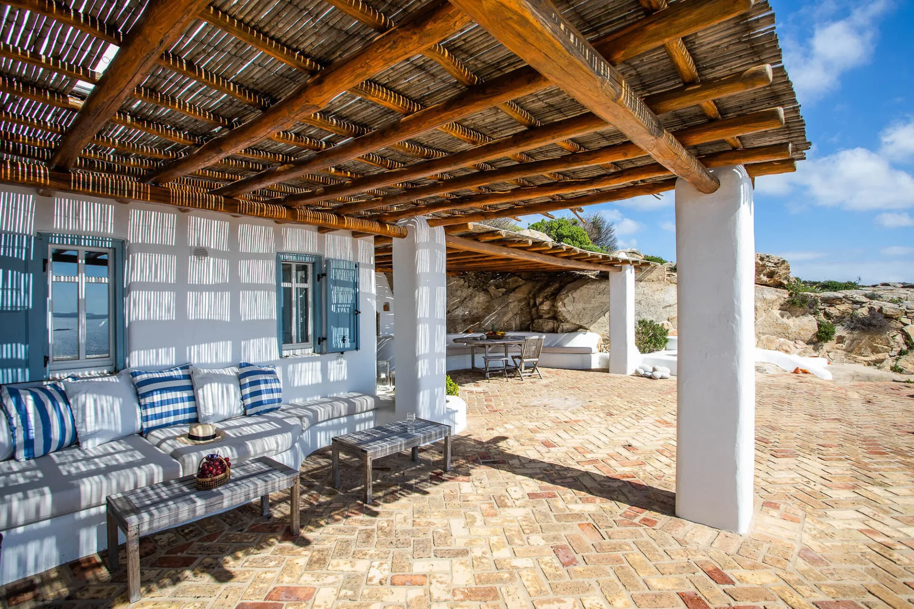 A shaded outdoor patio with seating beneath a wooden pergola.