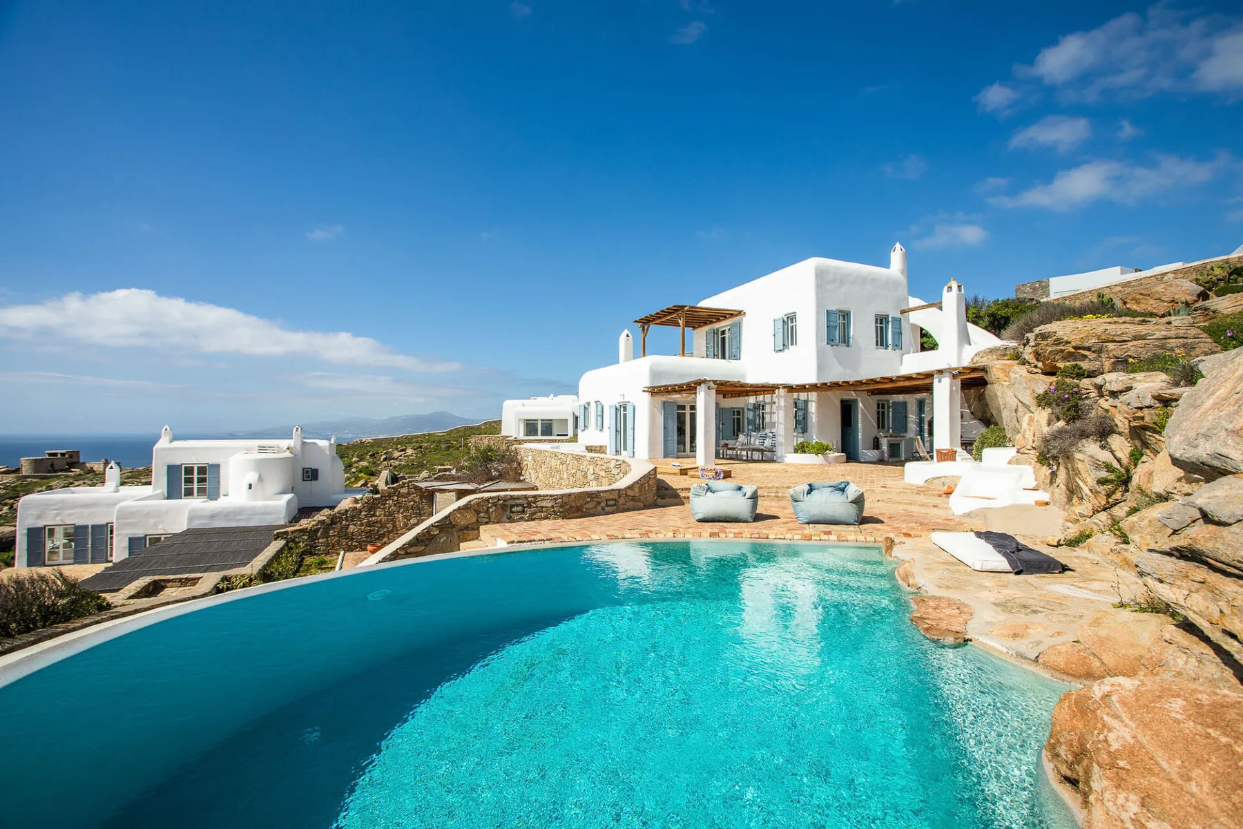 A hillside villa overlooks a swimming pool and the sea.