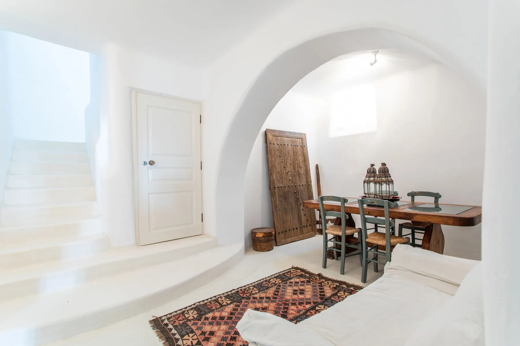 A white interior sitting area with a dining table beneath an arched alcove.