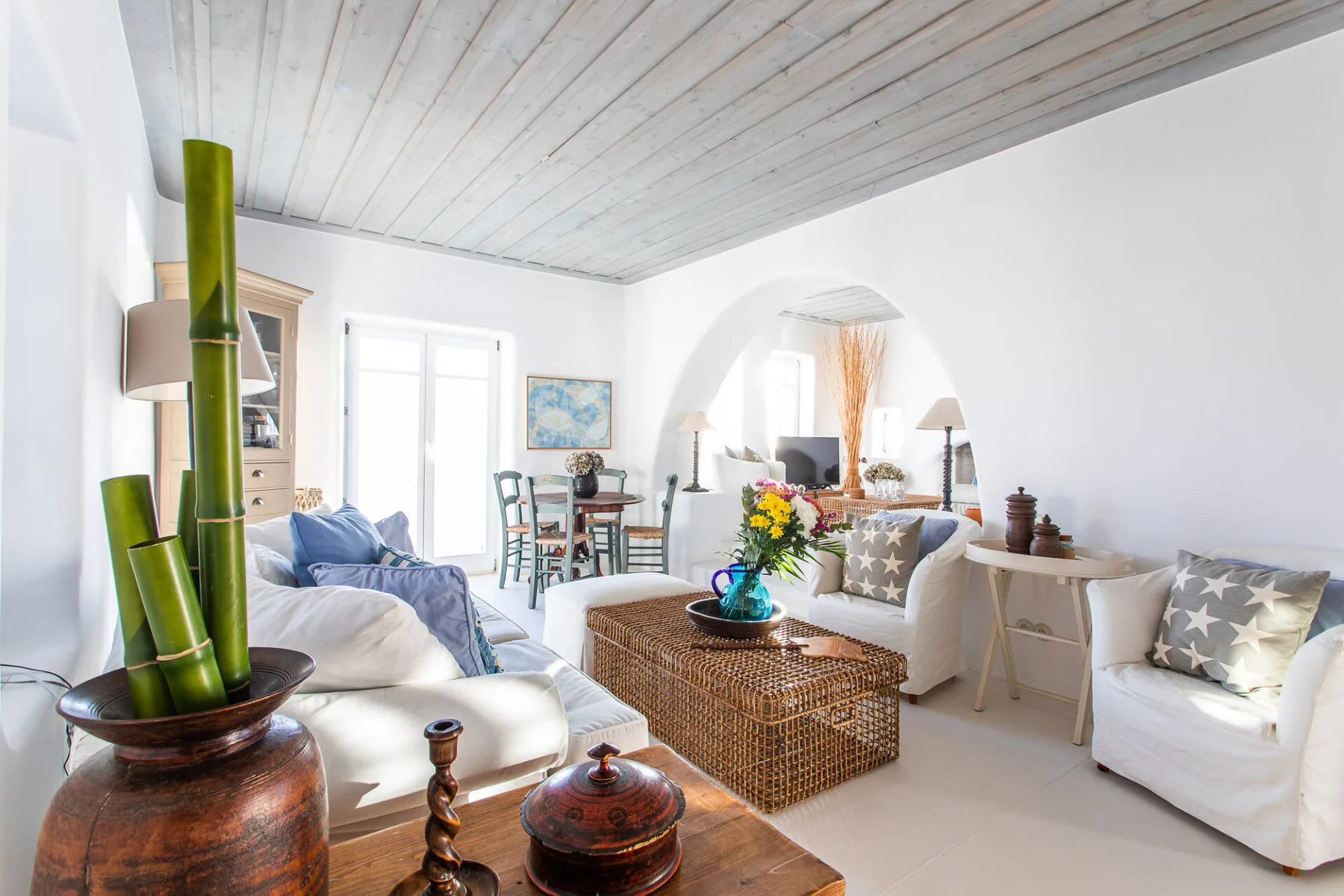 A bright living room with seating and a wicker coffee table.