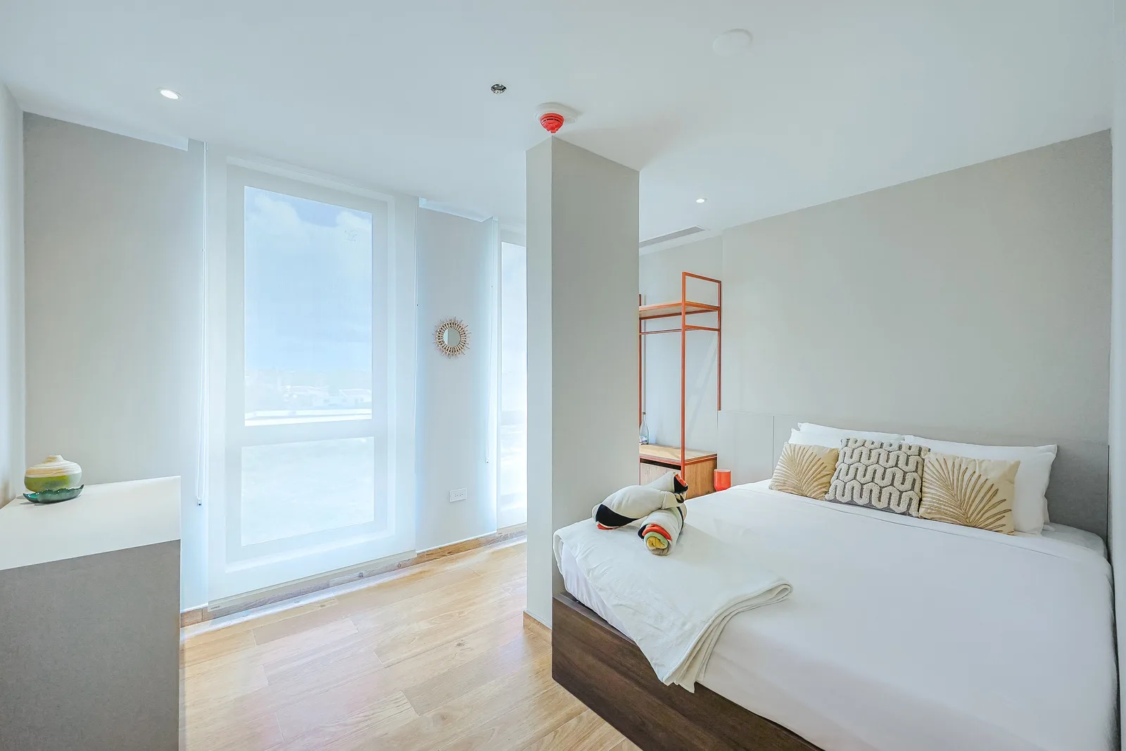 Sink into crisp linens in your serene bedroom, where tall windows fill the space with abundant natural light. The minimalist design and warm wood floors create a peaceful retreat for restful nights.