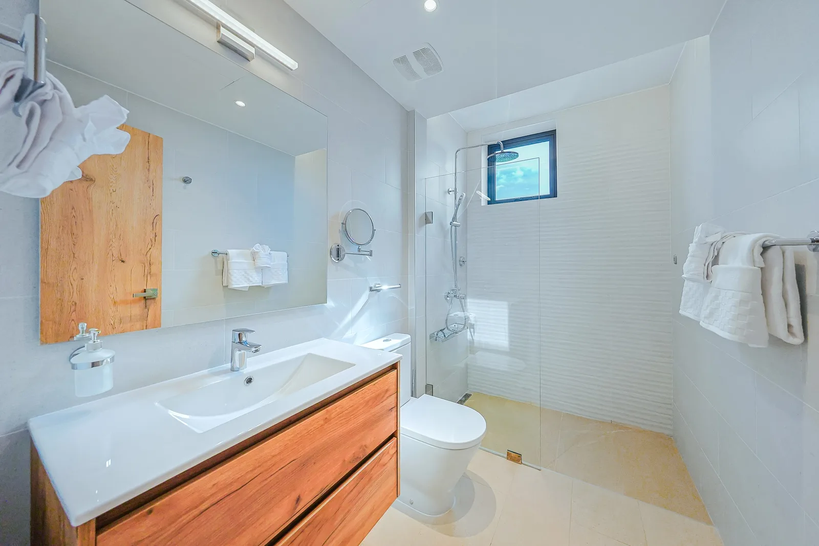 Step into your sleek, modern bathroom with a spacious glass-enclosed shower, warm wood vanity, and fluffy white towels waiting for you.