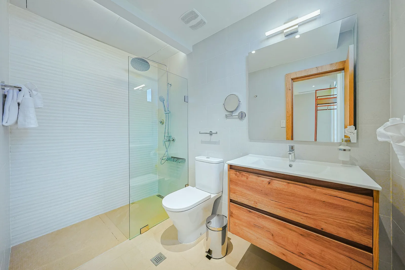Step into your sleek, modern bathroom featuring a spacious glass-enclosed shower and warm wood vanity that brings natural elegance to your daily routine.
