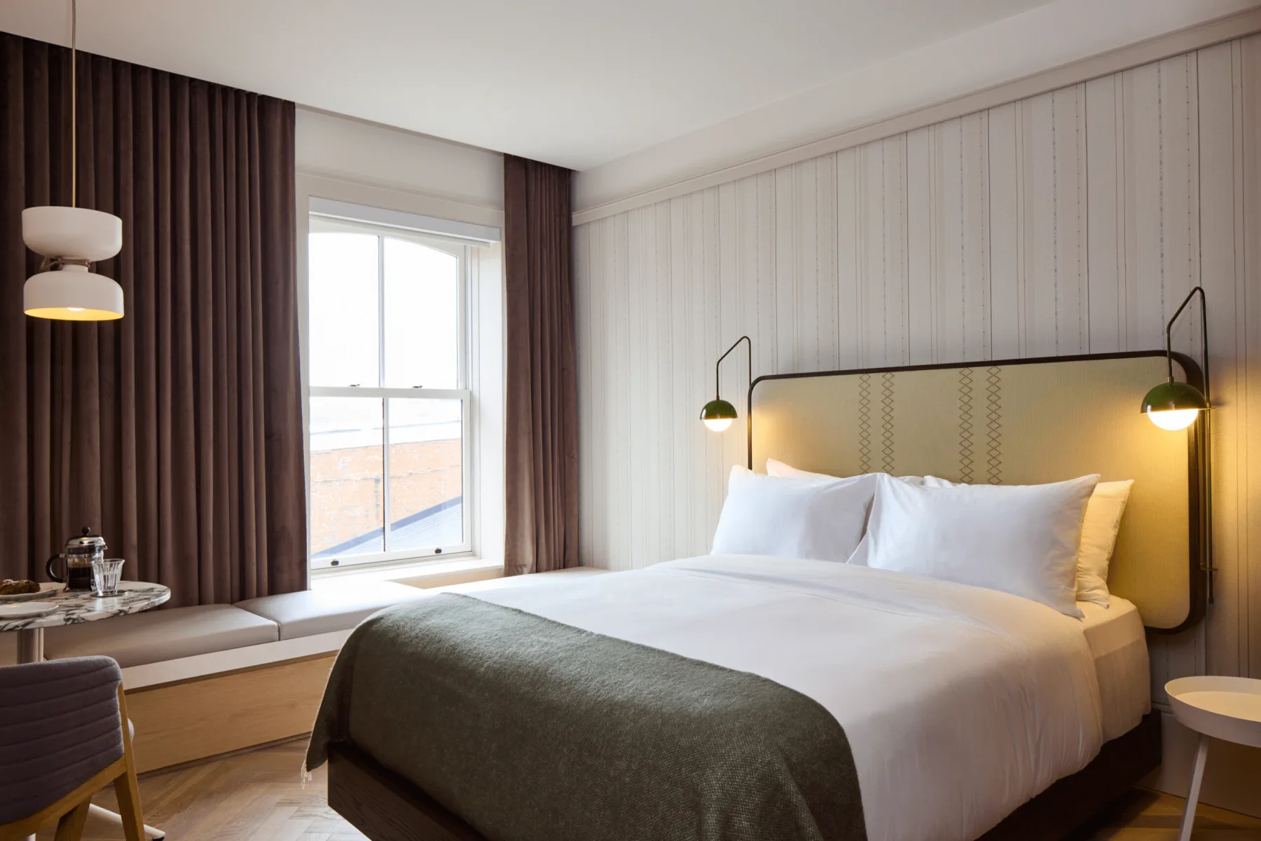 Cama y asientos junto al ventanal saliente en una habitación Cortland.