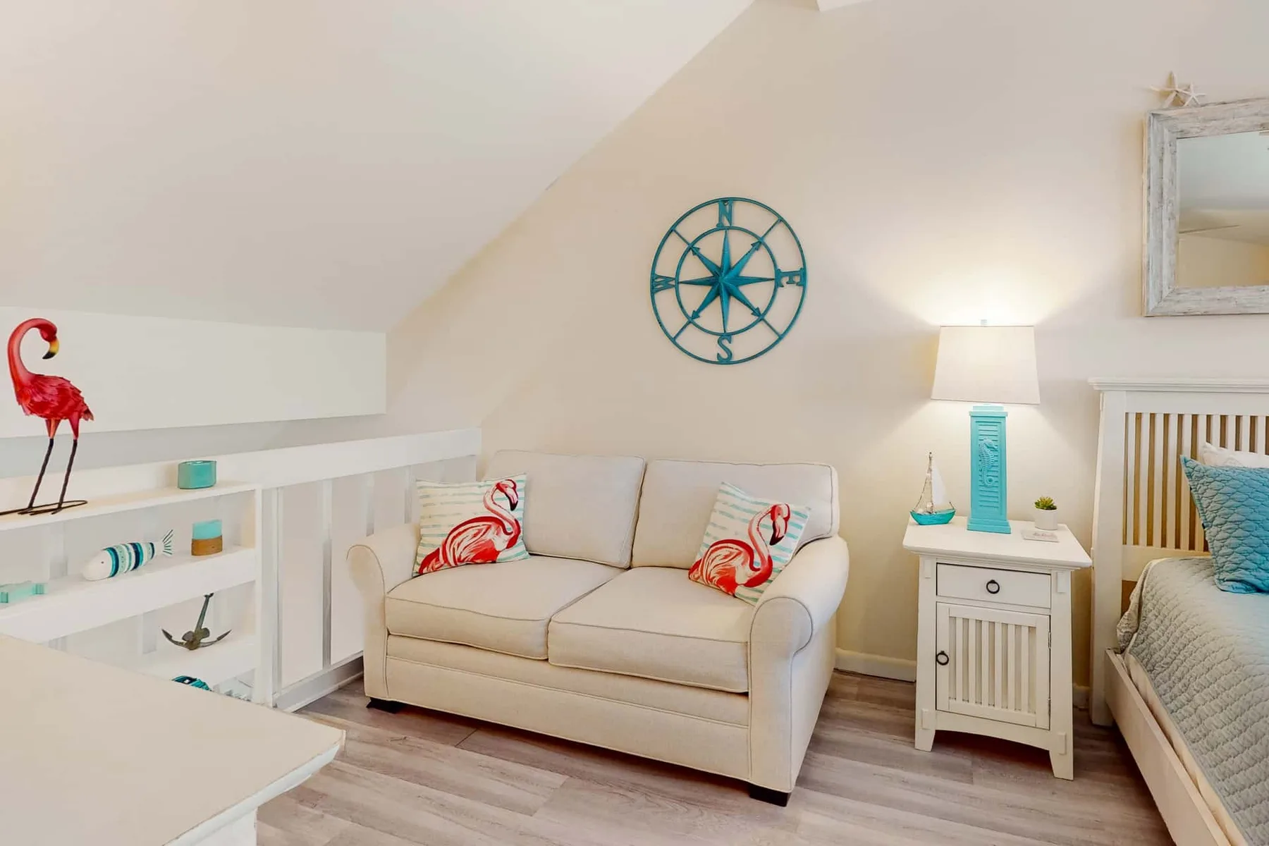 Un dormitorio luminoso con una cama, un pequeño sofá y un reloj náutico en la pared.