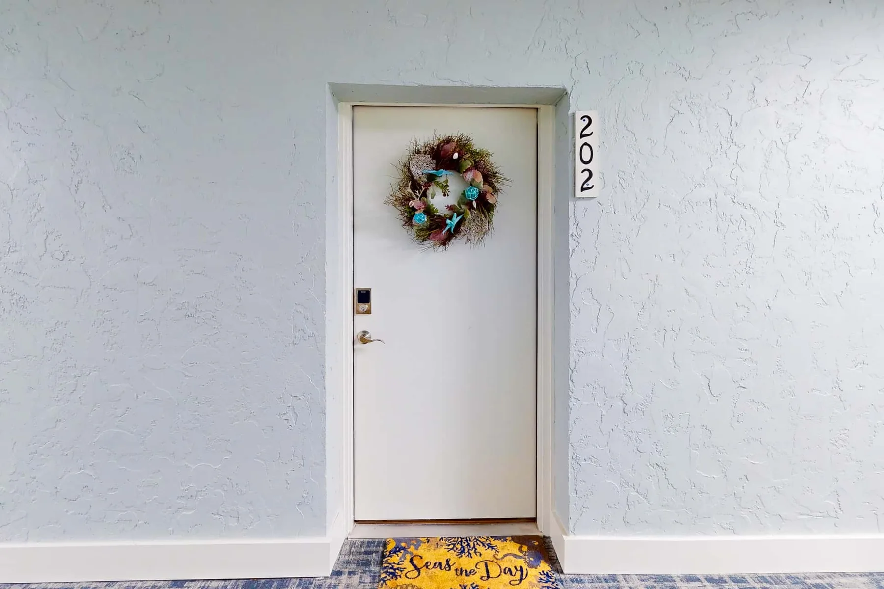 Una entrada exterior con una puerta blanca decorada con una corona.
