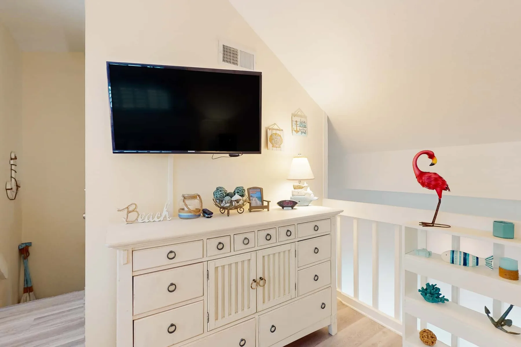 Una luminosa zona de estar en la planta superior tiene un mueble blanco bajo un televisor en la pared.
