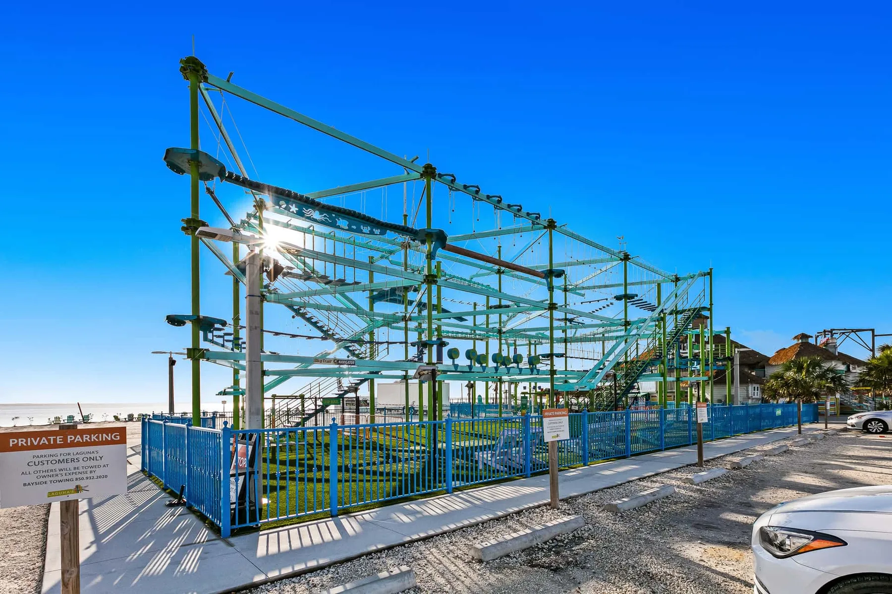 Una estructura exterior cercada con vigas verdes de metal se alza junto a una calle pavimentada.